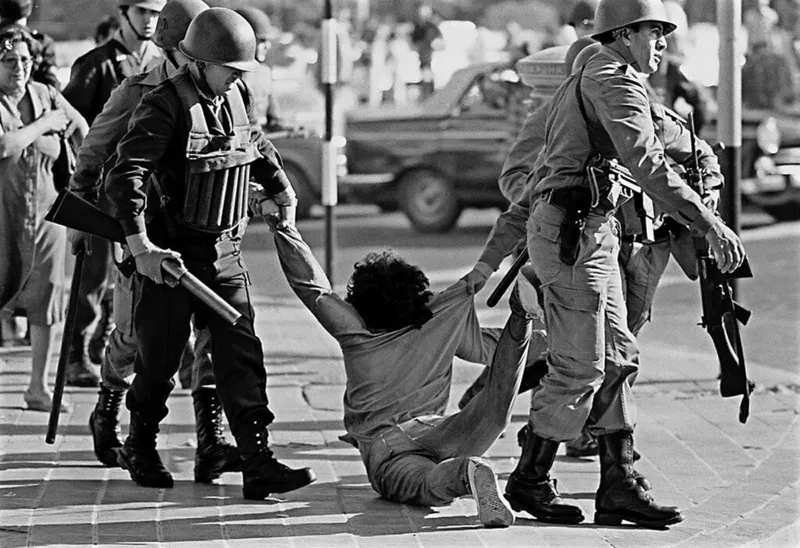 A detained protester being dragged by security forces.