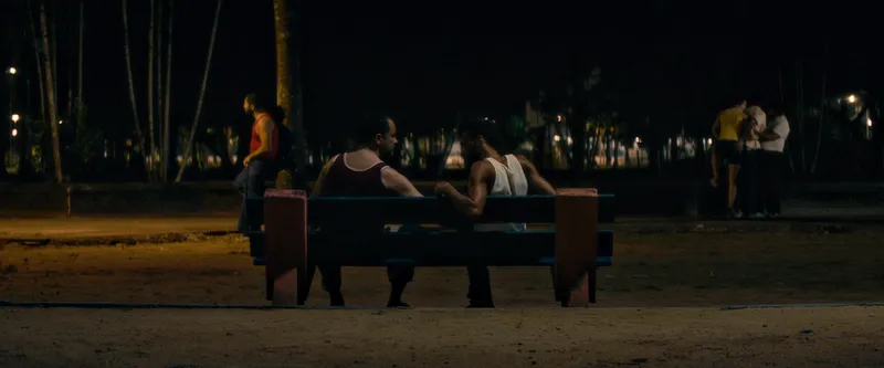 A tense nocturnal meeting in a public square captures the pervasive surveillance of the dictatorship era